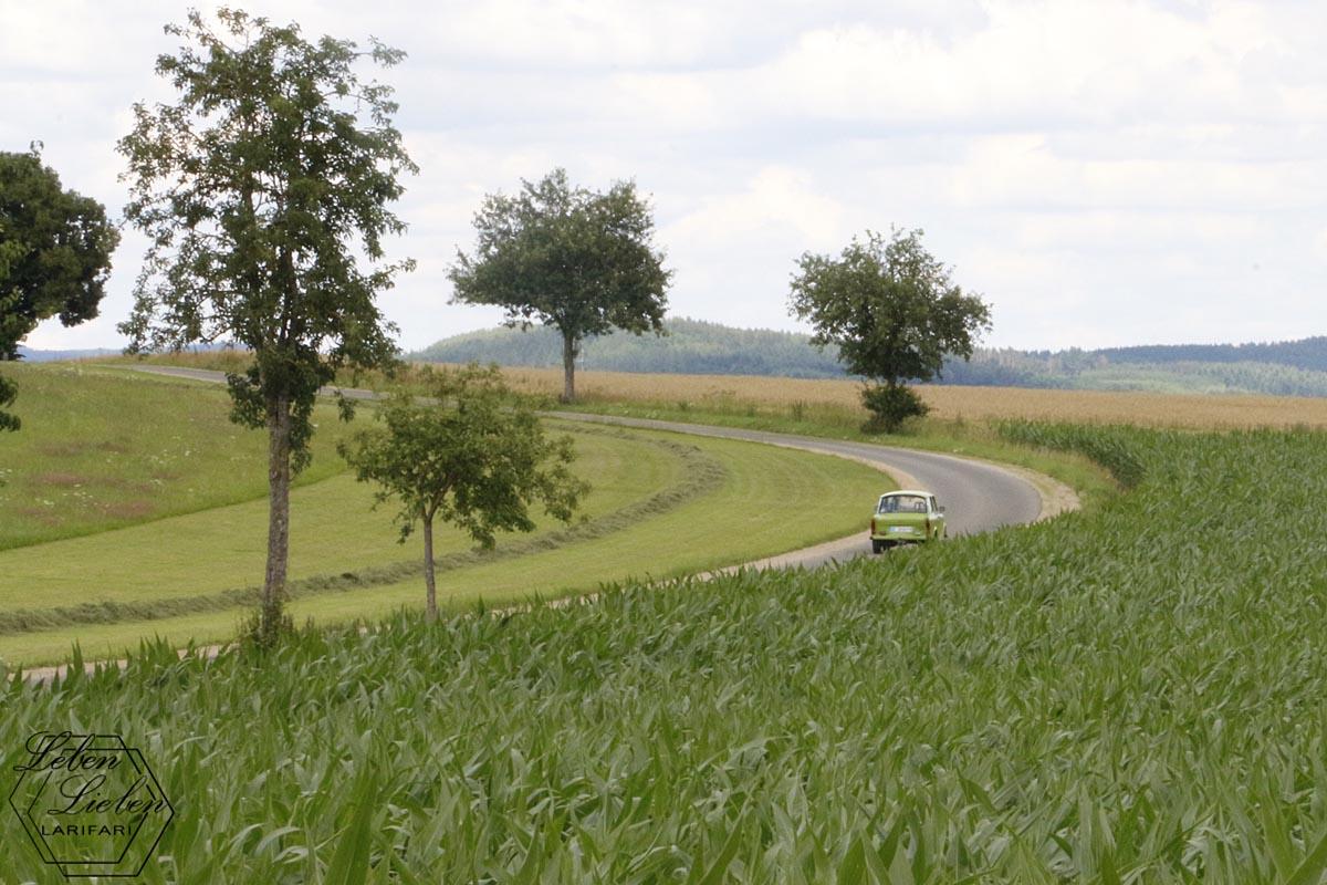 Parallelstraße: Ein Oldtimer fährt von einem Dorf ins nächste