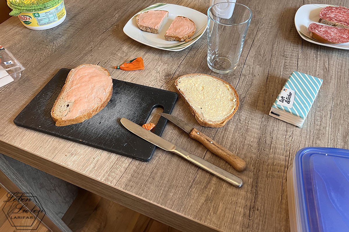 Brettchen und Messer liegen im Vordergrund, im Hintergrund ein Teller mit Frühstück