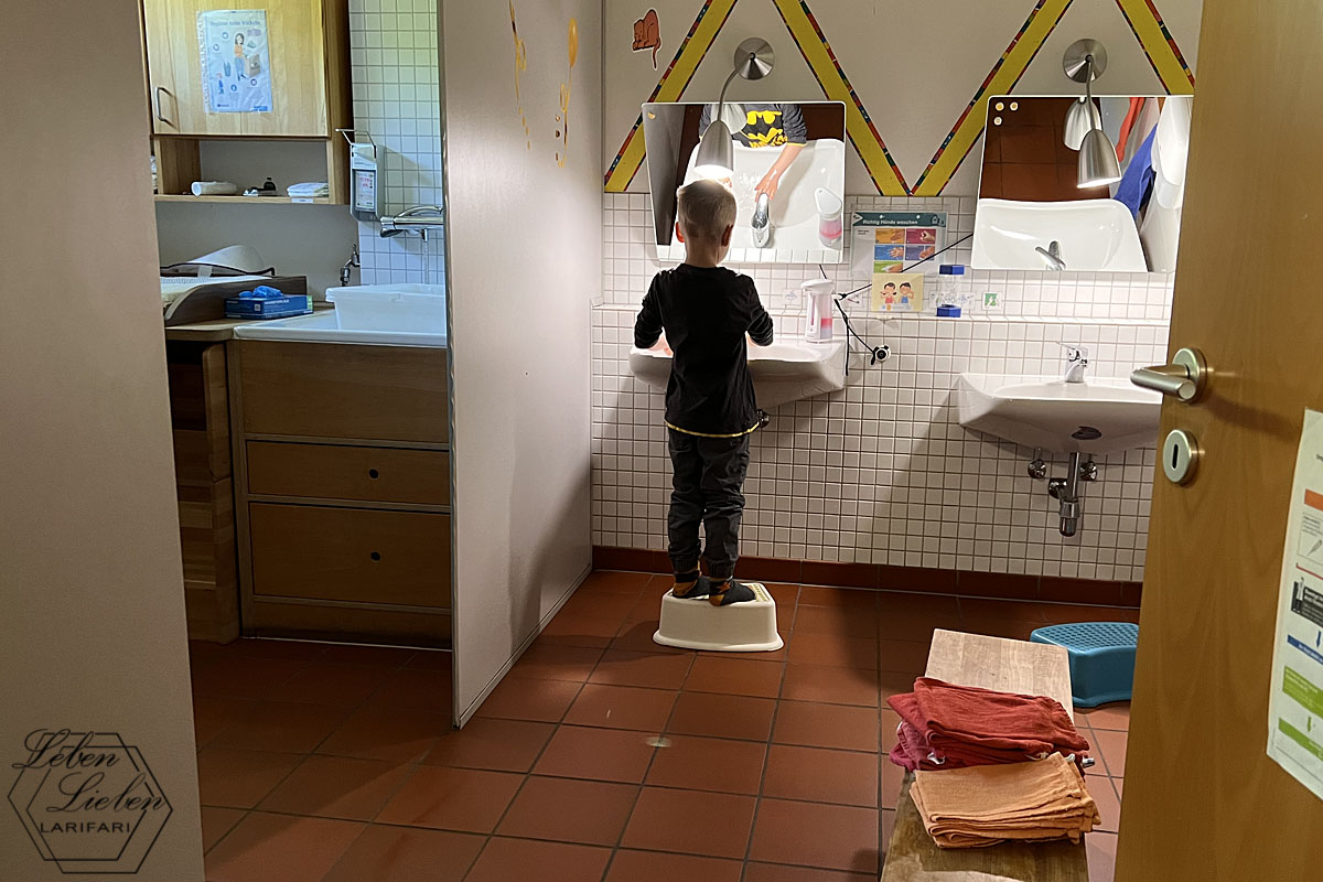 Ein Kind steht auf einem Hocker am Waschbecken