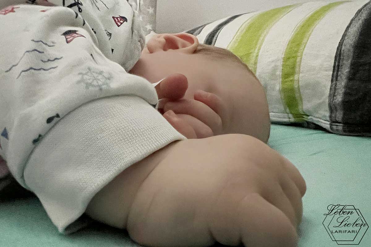 schlafendes Baby, Hände im Vordergrund verdecken das Gesicht