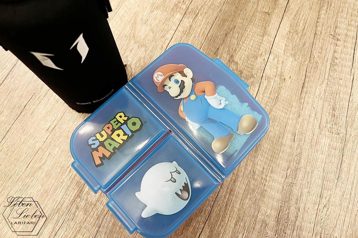 Brotdose mit Super Mario Aufdruck und Trinkflasche stehen auf dem Tisch