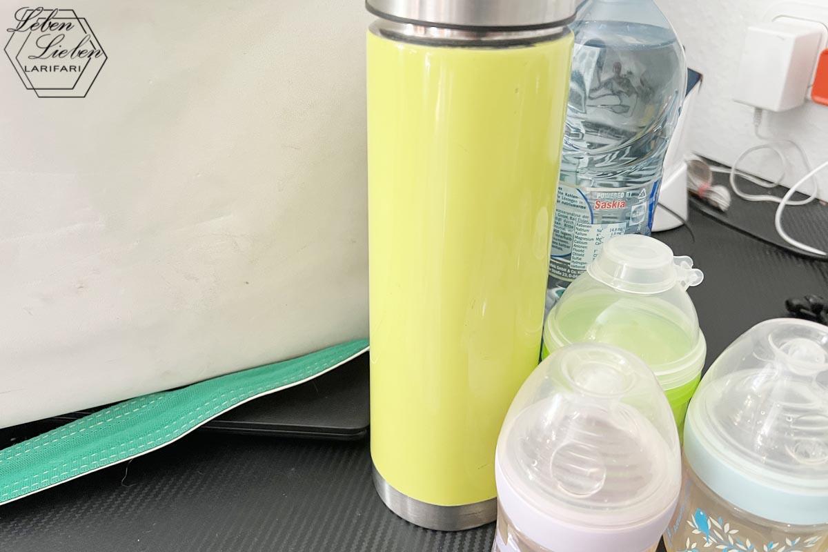 Tasche, Thermosflasche, Babymilchpulver und -fläschchen stehen auf der Anrichte