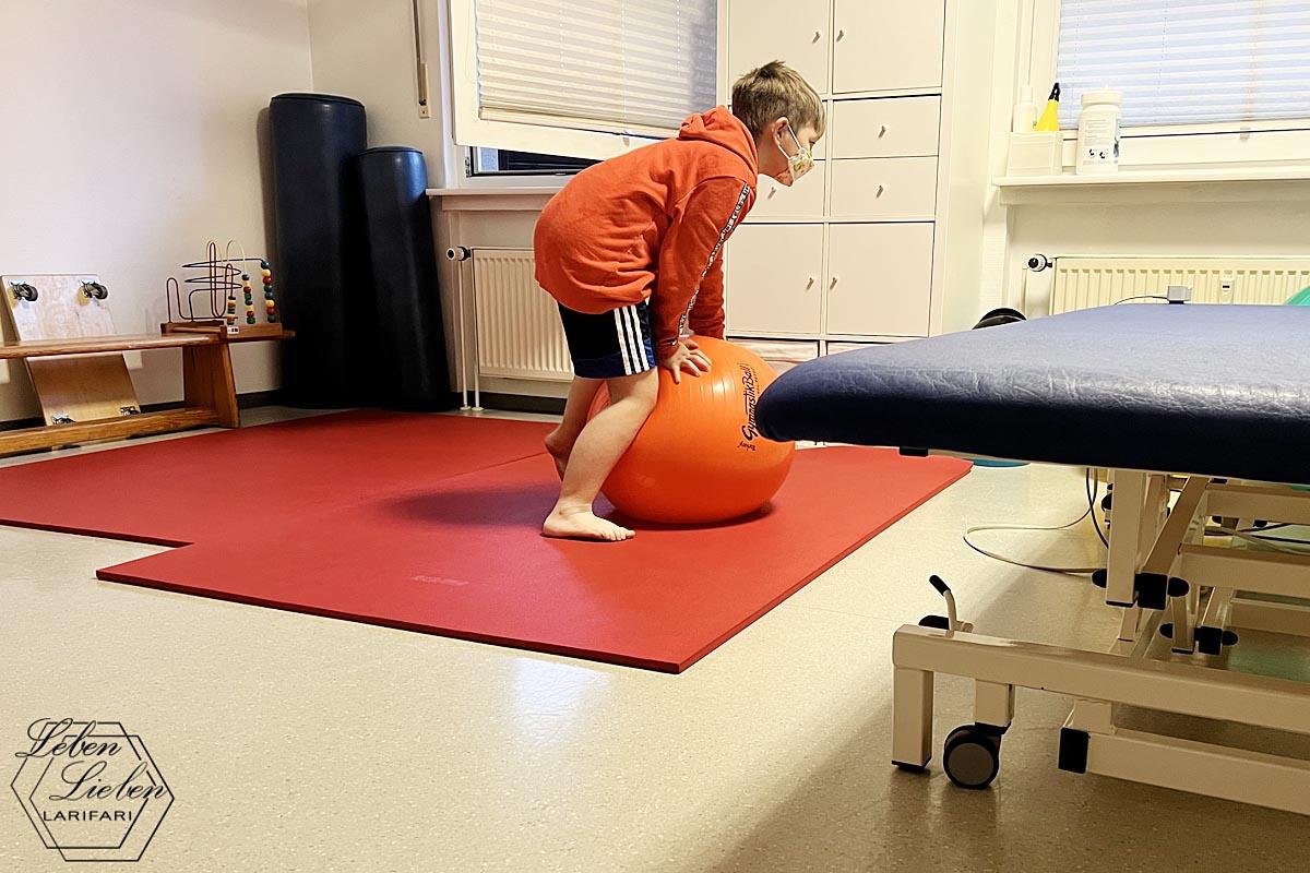 Das Schulkind kniet sich im Therapieraum auf einen Gymnastikball.