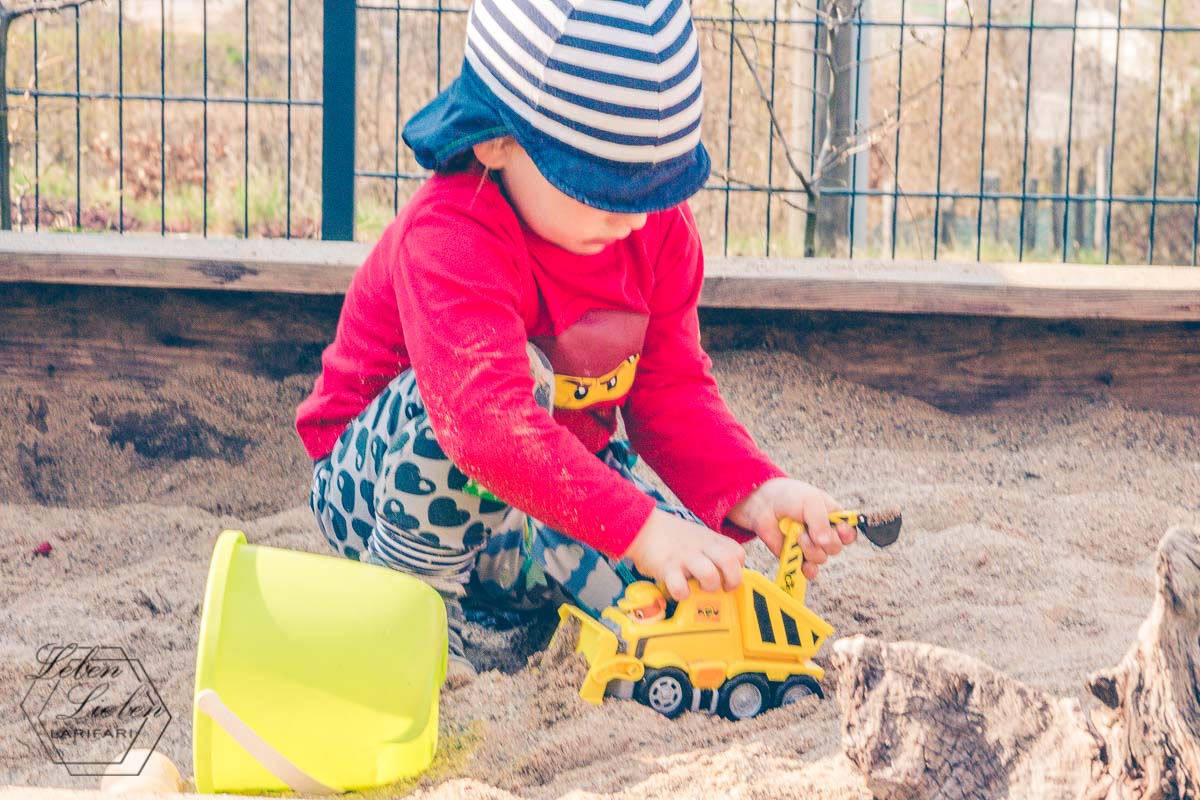 Ein Kind spielt mit Rubbles Fahrzeug im Sandkasten