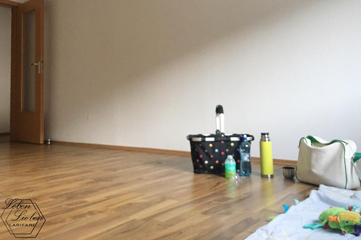 Ein leerer Raum, an der Wand steht ein Korb, davor einige Flaschen