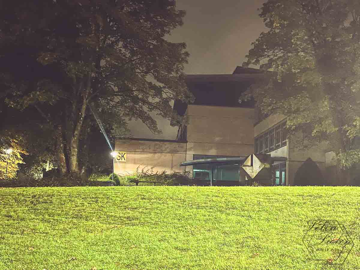 Beleuchtete Schule im dunkeln mit Rasenfläche davor