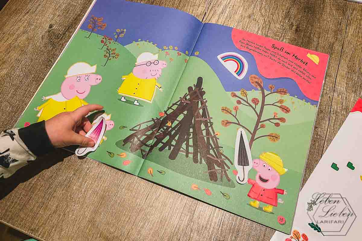 Ein Heft mit Peppa Wutz Abbildungen liegt auf dem Tisch, darauf sind Kinderhände mit Stickern zu sehen.